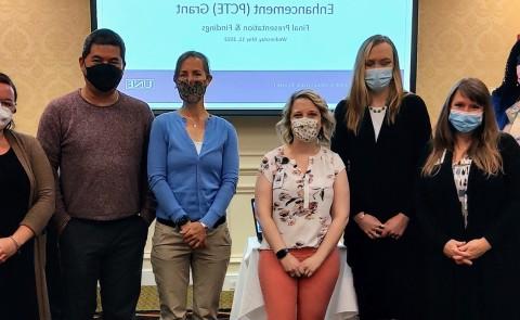 A number of health care preceptors pose for a photo against a slideshow